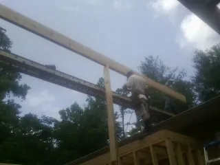 Carpenter setting a ridge beam over a new addition frame — Ice Dam Removal by Roofing Brothers in Jordan