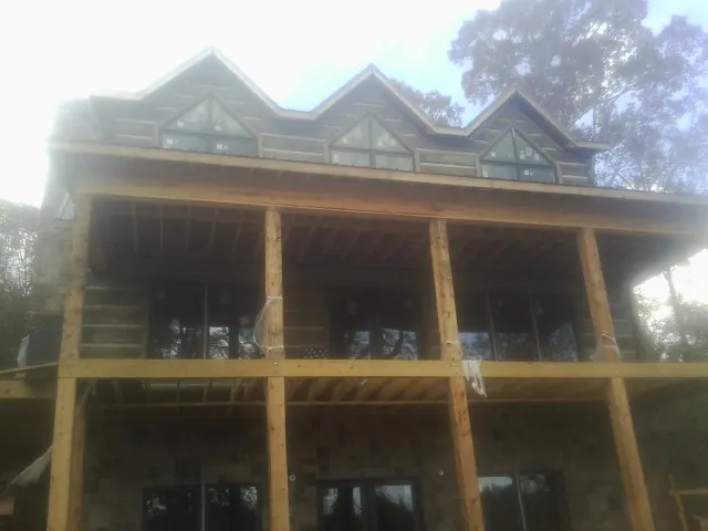 Dormers and porch framing on a large log home under construction — Roof Coating work by our crew in Jordan