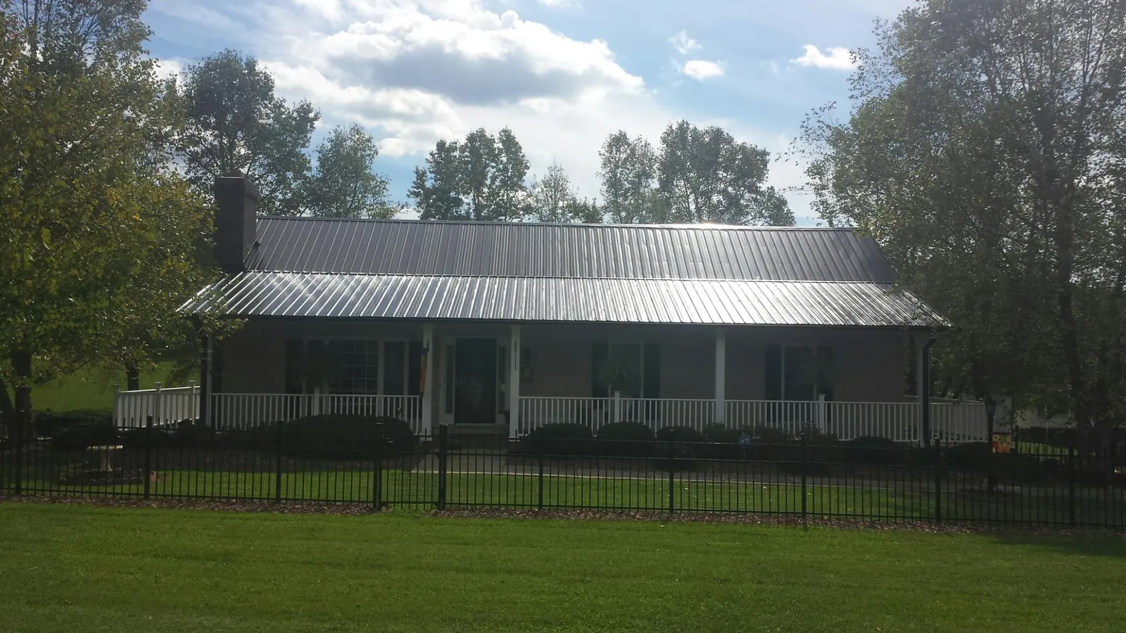 Gray metal roof on a brick ranch with a full width front porch — Gutter Guard Installation work by our crew in Jordan